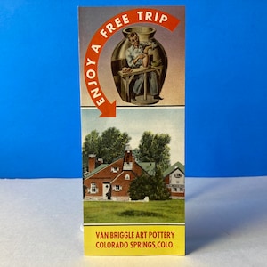 Könnte beinhalten: Ein rotes Backsteingebäude mit einem grünen Dach und einem Schild mit der Aufschrift "Van Briggle Art Pottery Colorado Springs, Colo.". Das Schild befindet sich unter einem Bild eines Mannes, der Töpferwaren herstellt.