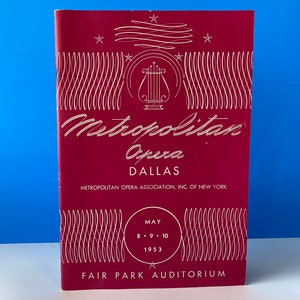 May include: A maroon Metropolitan Opera program from Dallas, with white text and decorative lines. The program includes the text "Metropolitan Opera Dallas" and the dates May 8-10, 1953, at Fair Park Auditorium.