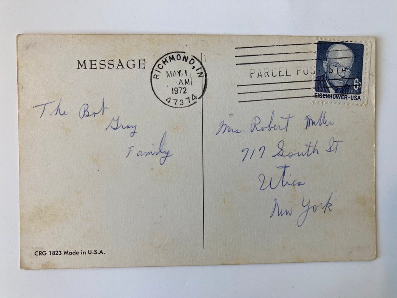 May include: Vintage postcard with handwritten message and address. The postcard has a postmark from Richmond, IN, dated May 1, 1972. A postage stamp featuring Eisenhower is in the upper right corner. The postcard is marked "CRG 1823 Made in U.S.A."