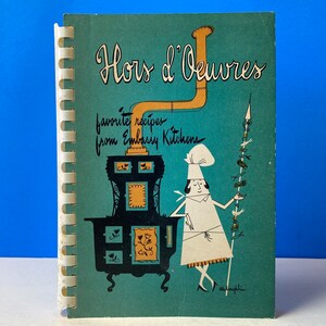 Puede incluir: Un libro de cocina azul verdoso con encuadernación en espiral titulado "Hors d'Oeuvres" con el texto "recetas favoritas de las cocinas de la embajada". La portada presenta una ilustración de dibujos animados de un chef con uniforme blanco y una estufa negra con una chimenea amarilla.