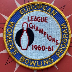 May include: A blue and gold embroidered patch with the text "European Women's Bowling Program League Champions 1960-61" and a red and white bowling pin graphic.