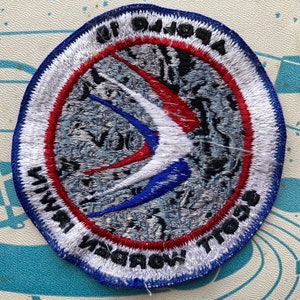 Peut inclure: Un &eacute;cusson brod&eacute; blanc, bleu et rouge avec un motif d'oiseau stylis&eacute; et le texte "NAVY TROOP 11"