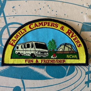 May include: Embroidered patch with a yellow border and a blue sky background. The patch features a white RV, a tent, and text that reads "FAMILY CAMPERS & RVERS" and "FUN & FRIENDSHIP".