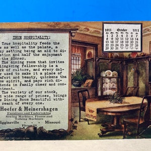 May include: A vintage postcard advertising a furniture and undertaking business called Hoefer & Meinershagen. The postcard features a photo of a dining room with a table, chairs, and a built-in hutch. The text on the postcard reads "True Hospitality!" and includes the business's address and phone number. The postcard also includes a calendar for October 1911.