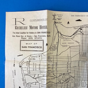 Op de afbeelding: Een vintage kaart van San Francisco, Californië, van het Richelieu Motor Hotel. De kaart is gedrukt met zwarte inkt op gebroken wit papier en bevat een gedetailleerde stratenkaart, bezienswaardigheden en de Golden Gate Bridge. Het logo en de contactgegevens van het hotel zijn ook zichtbaar.