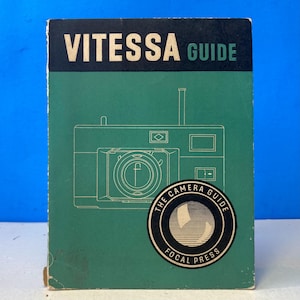 May include: Vintage "Vitesse Guide" book with a green cover and a black banner at the top. The cover features a line drawing of a camera and a circular emblem that reads "The Camera Guide" and "Focal Press".