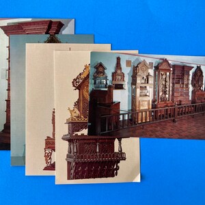 Pode incluir: Um conjunto de postais com imagens de móveis antigos de madeira, incluindo relógios e armários. Os postais estão dispostos sobre um fundo azul brilhante, mostrando o artesanato detalhado dos móveis.