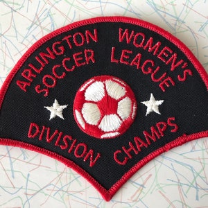 May include: A black and red embroidered patch with a soccer ball, two stars, and the text "Arlington Soccer League's Division Champs".