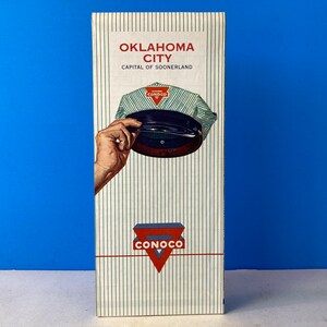 May include: A vintage travel guide to Oklahoma City, the capital of Oklahoma. The cover features a Conoco gas station logo and a blue and white striped cap.