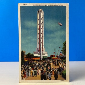May include: A vintage postcard showing the Giant Thermometer at the 1933-34 Chicago World's Fair. The thermometer is a tall, white structure with a red and white thermometer scale. People are walking in front of the thermometer, and a blimp is flying in the sky.