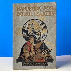 May include: A vintage book titled "Handbook for Patrol Leaders" with a cover illustration of Boy Scouts camping and a Boy Scout emblem. The book is published by Boy Scouts of America.