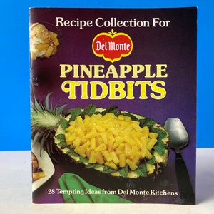 Könnte beinhalten: Ein Vintage-Kochbuch mit einem violetten Einband, auf dem eine Schüssel mit Ananasstücken und der Text "Recipe Collection For Del Monte Pineapple Tidbits 28 Tempting Ideas from Del Monte Kitchens" zu sehen ist.