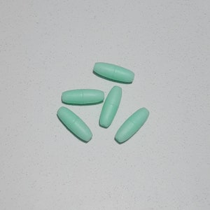 May include: Five light green oval-shaped plastic beads. The beads are smooth and have a matte finish.