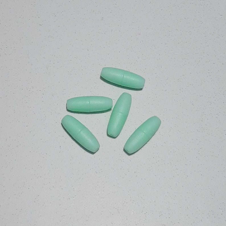 May include: Five light green oval-shaped plastic beads. The beads are smooth and have a matte finish.