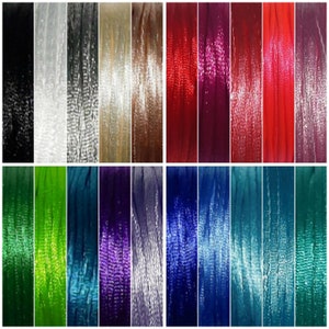 May include: A collection of 16 spools of embroidery floss in various colours, including black, white, red, green, blue, purple, and brown. The floss is arranged in two rows of eight spools each.