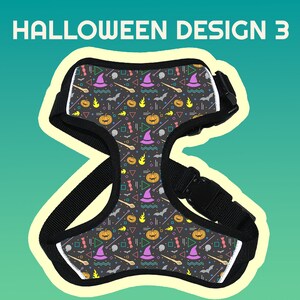 May include: Black adjustable dog harness with a Halloween themed pattern. The pattern features pumpkins, witches hats, bats, and other Halloween symbols in bright colors on a dark gray background.