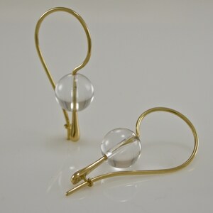 Puede incluir: Un par de pendientes de oro con detalles de bola de cristal transparente.