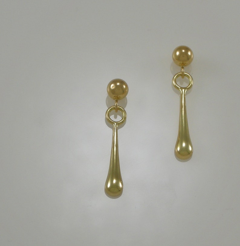 Pode incluir: Um par de brincos de ouro com uma bola redonda no topo e um pingente em forma de l&aacute;grima.