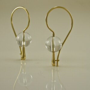 Puede incluir: Un par de pendientes de oro con cuentas de cristal transparente. Los pendientes tienen un dise&ntilde;o simple y elegante.