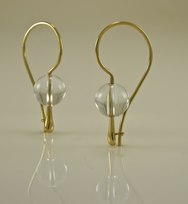 Puede incluir: Un par de pendientes de oro con cuentas de cristal transparente. Los pendientes tienen un dise&ntilde;o simple y elegante.