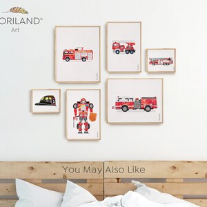 Op de afbeelding: Een set ingelijste prints met rode brandweerauto's, een brandweerhelm en een robot. De prints zijn gerangschikt op een witte muur boven een houten hoofdeinde. De tekst "You May Also Like" is zichtbaar onder de prints.