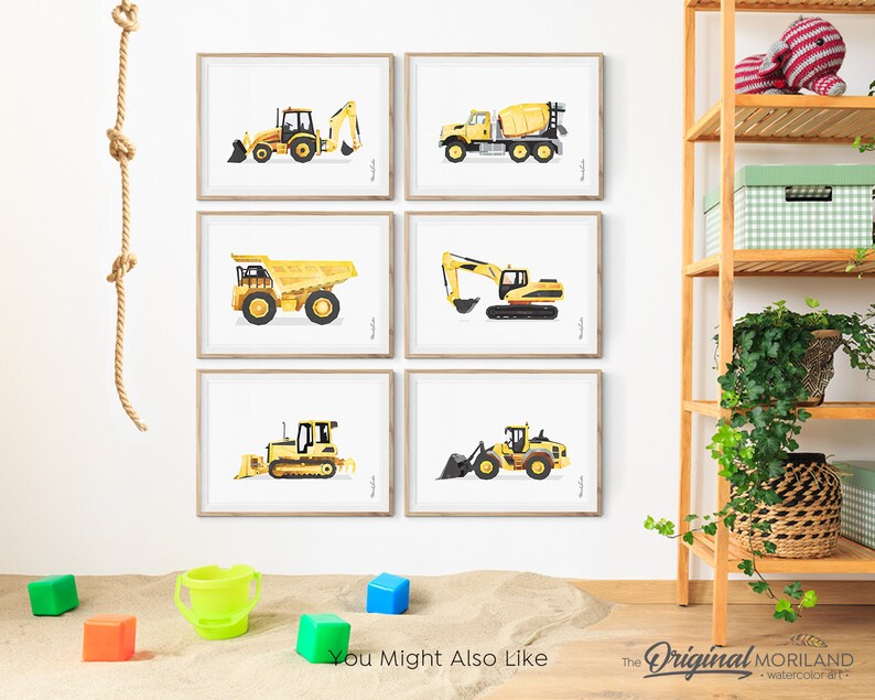 May include: Six framed prints of yellow construction vehicles, including a bulldozer, excavator, dump truck, and cement mixer. The prints are displayed on a white wall with a rope hanging on the left side. The prints are in a nursery or playroom setting.