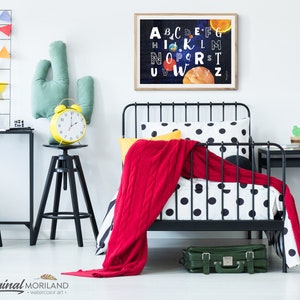 May include: A black metal bed frame with a white and black polka dot duvet cover and a red blanket. A yellow alarm clock sits on a black stool next to a green cactus pillow. A framed print of the alphabet with planets and stars hangs on the wall.