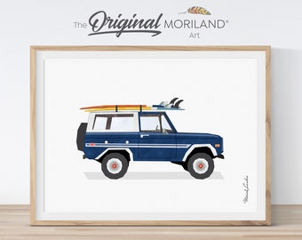 May include: A framed print featuring a blue vintage SUV with surfboards on top. The vehicle has white accents and a spare tire on the back. The artwork is set against a white background, with the text "The Original Moriland Art" at the top.