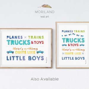Op de afbeelding: Twee ingelijste prints met een witte achtergrond en kleurrijke tekst die "PLANES &times; TRAINS TRUCKS & TOYS there's nothing QUITE LIKE LITTLE BOYS!" luidt. De prints zijn in een houten lijst en hangen aan een witte muur.