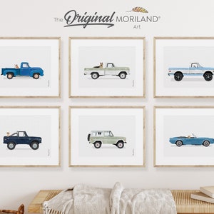 May include: Six framed prints of vintage trucks and cars with dogs in the driver's seat. The prints are in a variety of colors, including blue, green, and white. The text "The Original MORILAND Art" is at the top of the image.