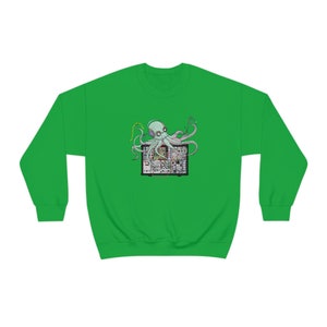 Può includere: Una felpa verde con una grafica di un polpo con cuffie che siede su un sintetizzatore.