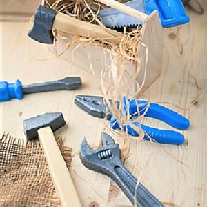 Op de afbeelding: Een set speelgoedgereedschap in een houten gereedschapskist, inclusief een hamer, een moersleutel, een tang, een schroevendraaier en een zaag. De gereedschappen zijn gemaakt van plastic en zijn in felle kleuren geverfd.