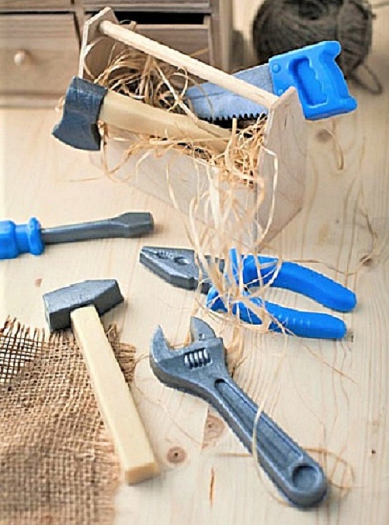 Op de afbeelding: Een set speelgoedgereedschap in een houten gereedschapskist, inclusief een hamer, een moersleutel, een tang, een schroevendraaier en een zaag. De gereedschappen zijn gemaakt van plastic en zijn in felle kleuren geverfd.