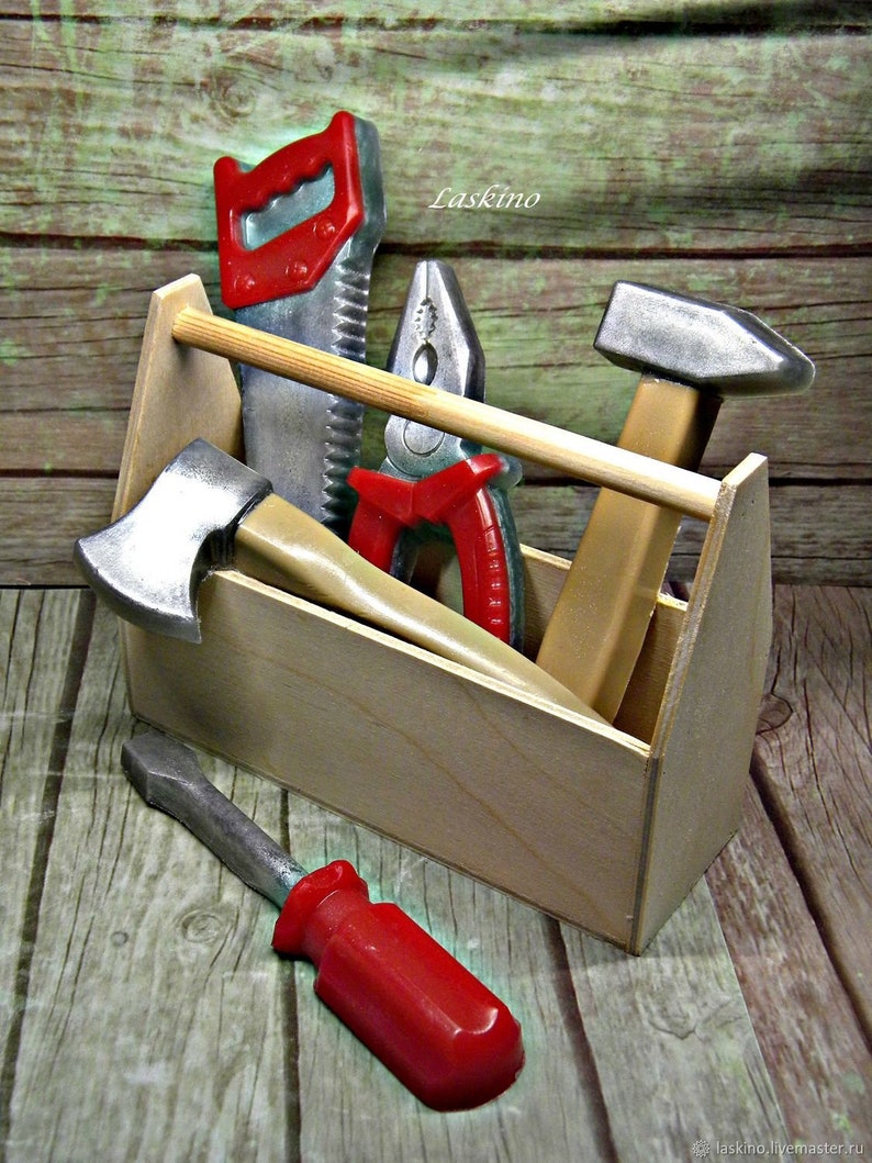 Op de afbeelding: Een houten gereedschapskist gevuld met speelgoedgereedschap, waaronder een zaag, een tang, een hamer, een bijl en een schroevendraaier. De gereedschappen zijn rood en zilver geverfd.