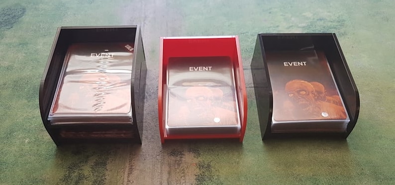 K&ouml;nnte beinhalten: Drei Kartenhalter, einer rot und zwei schwarz, jeder mit einem Kartenspiel darin. Die Karten haben den Aufdruck "EVENT" aufgedruckt.