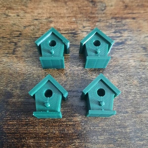 May include: Four miniature green birdhouses with a small hole in the front of each. The birdhouses are made of plastic and have a simple design.