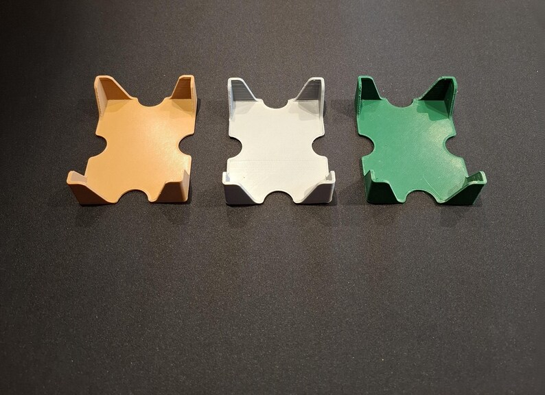 K&ouml;nnte beinhalten: Drei Kartenhalter aus Plastik in verschiedenen Farben: Orange, Wei&szlig; und Gr&uuml;n. Die Halter sind so konzipiert, dass sie ein Kartenspiel aufrecht halten.