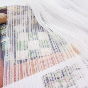 May include: White sheer fabric with vertical stripes. The fabric has a fine mesh texture.