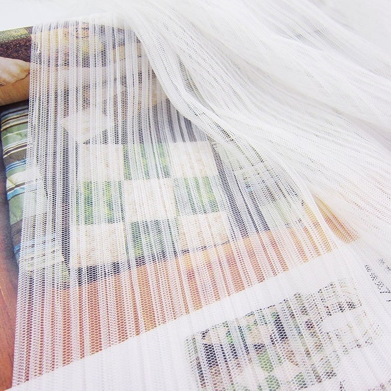 May include: White sheer fabric with vertical stripes. The fabric has a fine mesh texture.