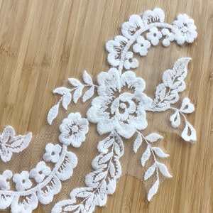 May include: White lace trim with floral embroidery. The lace features delicate flowers and leaves, creating a romantic and elegant design.