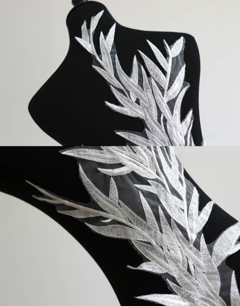 May include: White embroidered lace applique with a delicate leaf design. The lace is on a sheer mesh background.