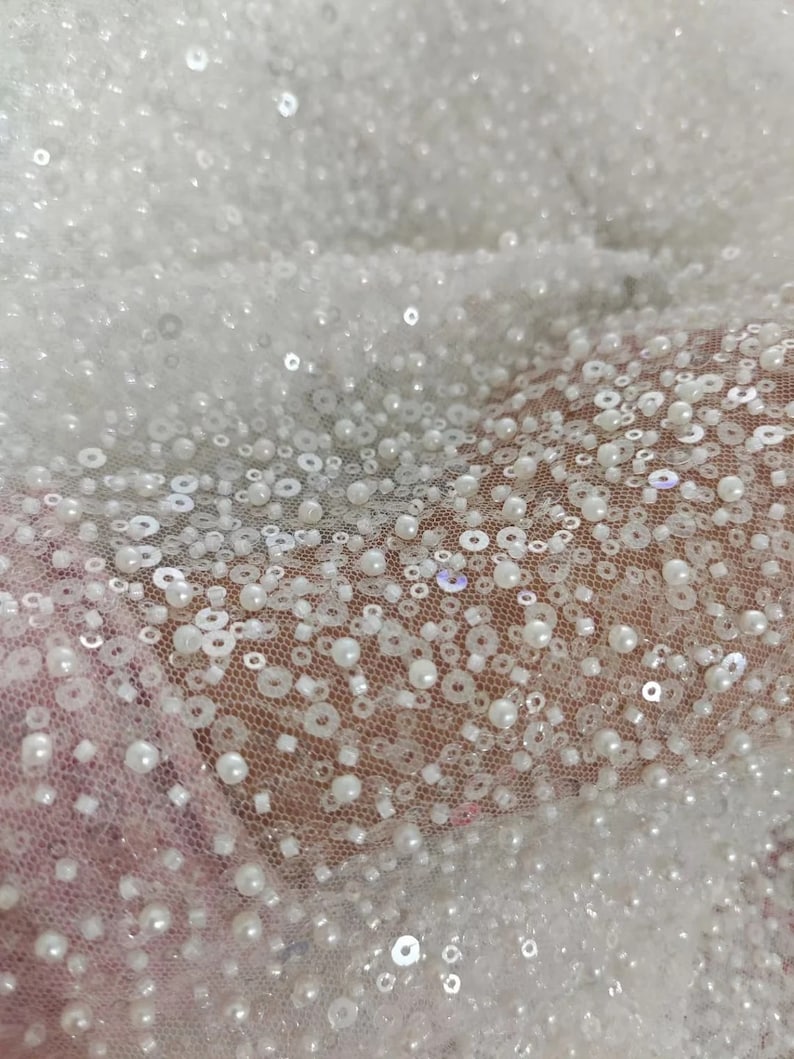 May include: White beaded fabric with a delicate mesh backing. The beads are small and round, creating a shimmering effect.