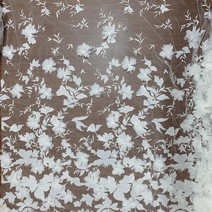 May include: White floral lace fabric with a textured, raised design. The lace features a repeating pattern of flowers and leaves.