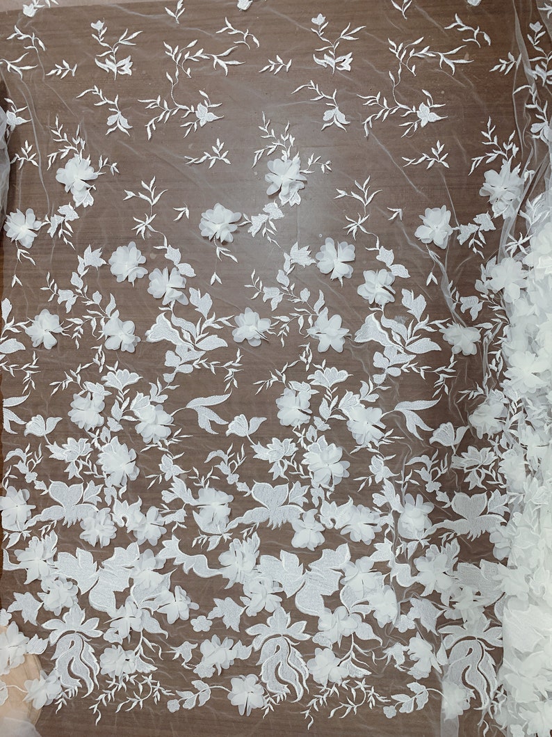 May include: White floral lace fabric with a textured, raised design. The lace features a repeating pattern of flowers and leaves.