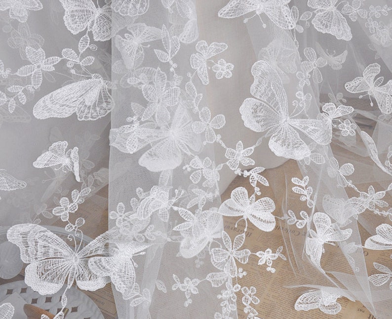 Pu&ograve; includere: Tessuto bianco trasparente con motivi di farfalle ricamate. Il tessuto &egrave; delicato, arioso e perfetto per l'artigianato o per aggiungere un tocco di eleganza a qualsiasi progetto.