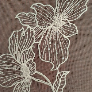 May include: White floral embroidery with sequins on a brown mesh fabric.