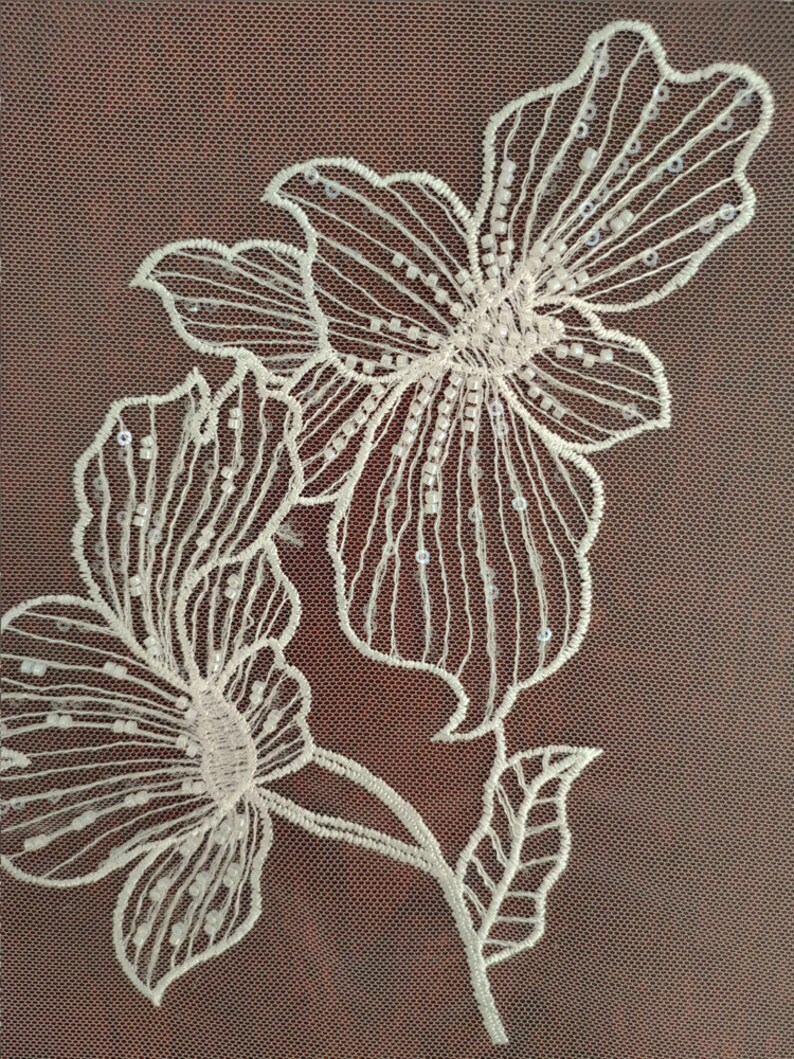 May include: White floral embroidery with sequins on a brown mesh fabric.