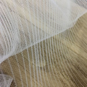 May include: White tulle fabric with a striped pattern. The fabric is soft and delicate, and it has a slightly shimmery finish.