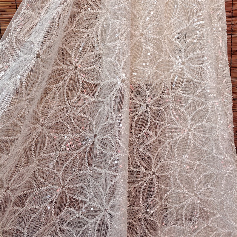 Peut inclure: Tissu blanc transparent avec un motif floral d&eacute;licat compos&eacute; de paillettes. Le tissu a un l&eacute;ger &eacute;clat et est parfait pour ajouter une touche d'&eacute;l&eacute;gance &agrave; tout projet.