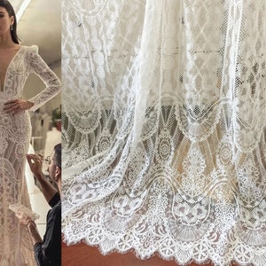 May include: White lace fabric with a delicate floral pattern. The lace has a scalloped edge and is perfect for crafting, sewing, or decorating.